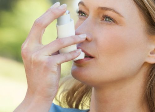 Woman with asthma using an inhaler