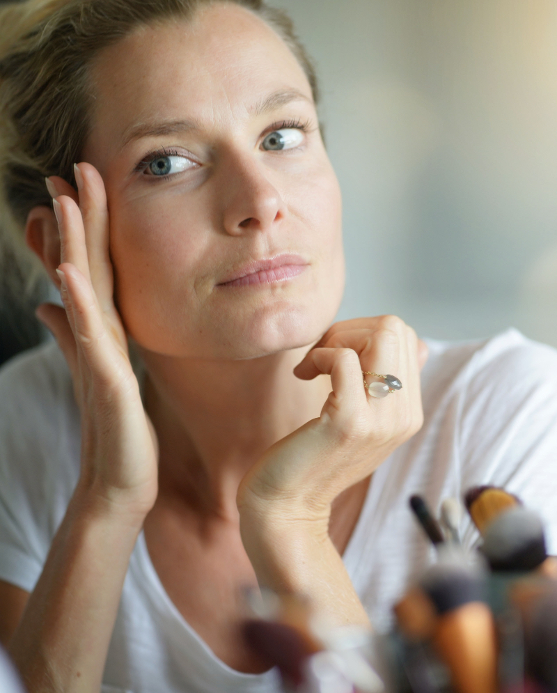 Middle age woman looking at her face and skin in the mirror